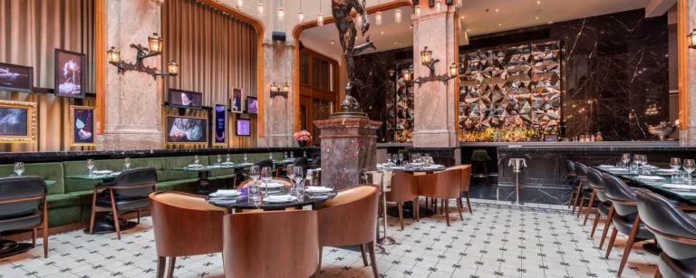 Restaurantzaal met gedekte tafels, leren stoelen en een marmeren bar