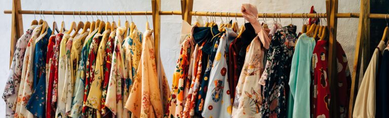 Kledingrek met houten hangers vol bedrukte jasjes in allerlei kleuren