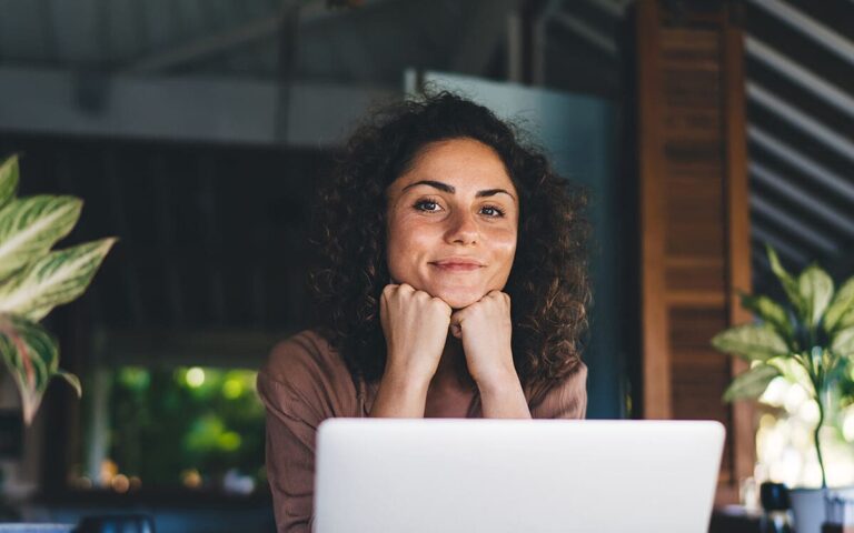 Een vrouw achter een laptop tussen groene planten